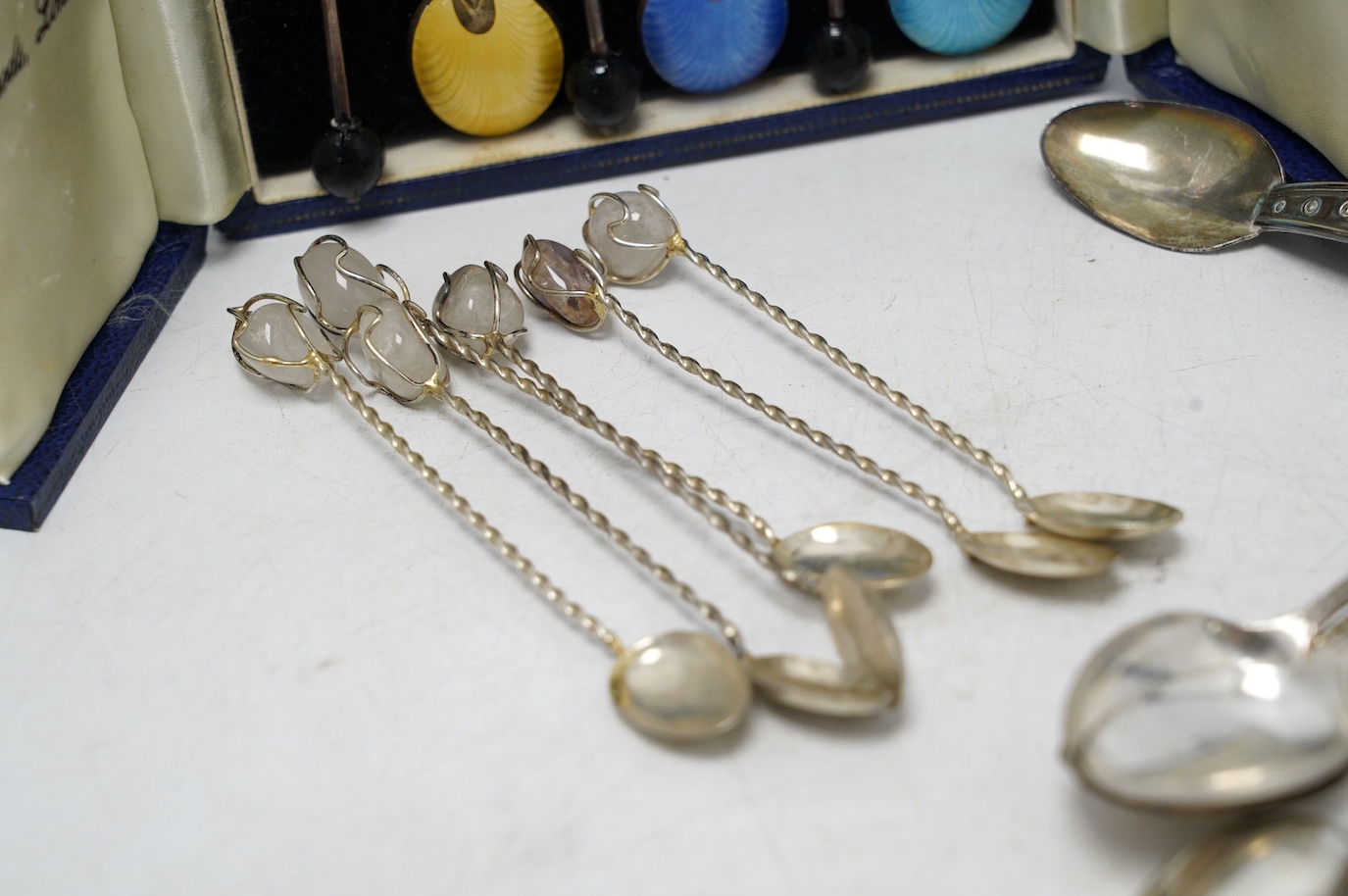 A set of ten George V silver coffee spoons, Birmingham, 1931, a later cased set of six silver and polychrome enamel bean end coffee spoons, a turquoise set sterling spoon, and a set of six white metal spoons with hardsto